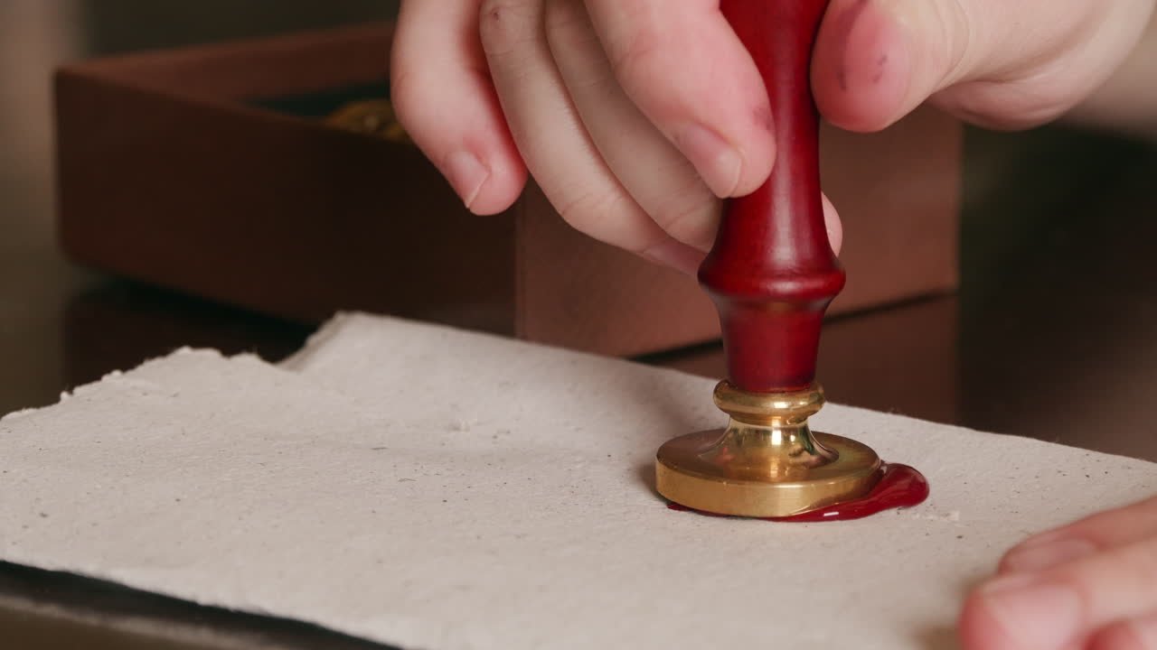 Pressing a brass signet stamp into warm wax